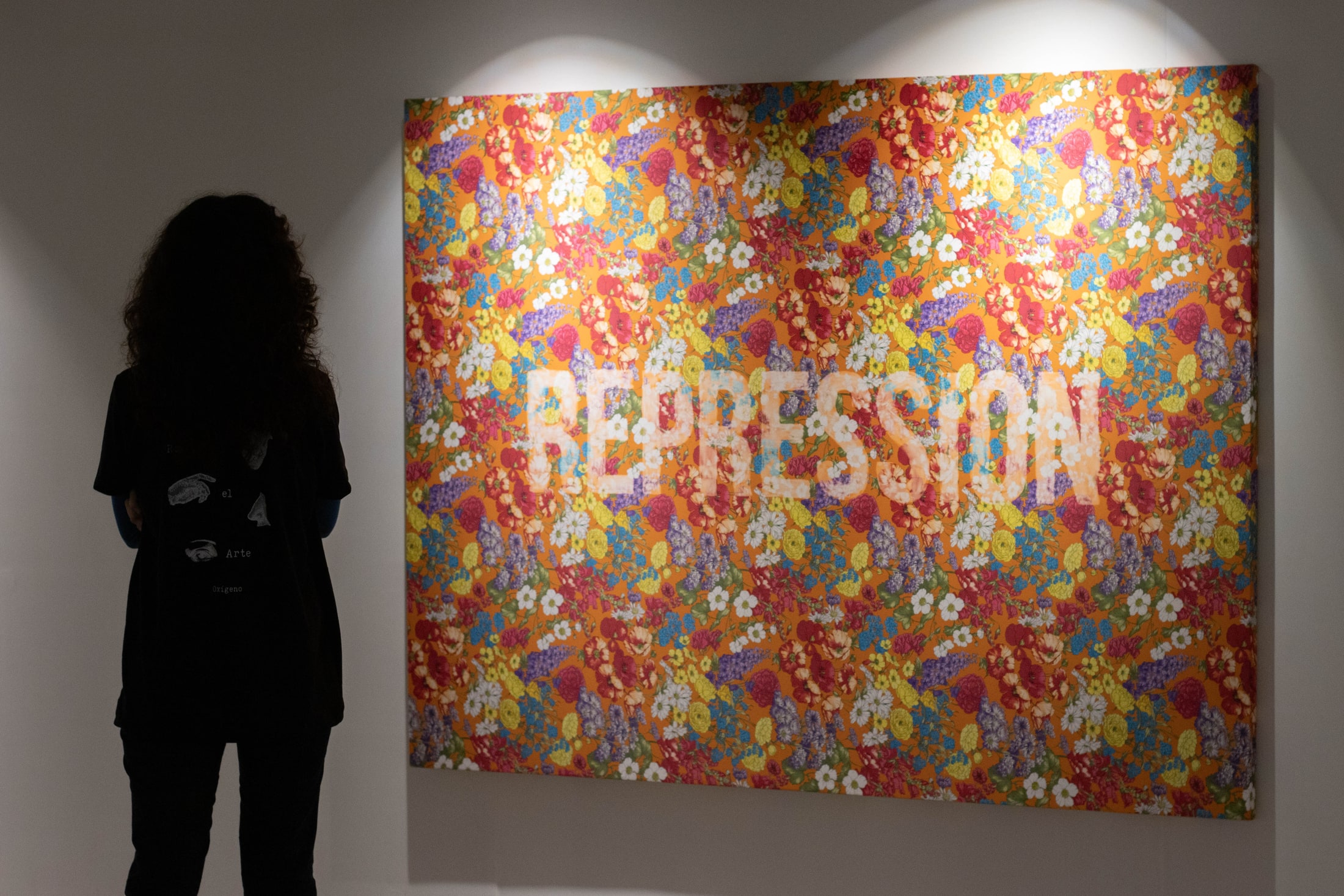 Una visitante observa una pintura colorida en Oxígeno Feria de Arte